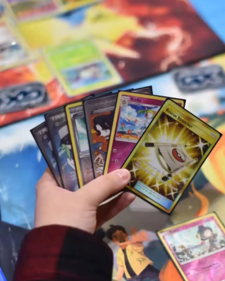 A hand of Pokémon cards held over a playmat mid-game